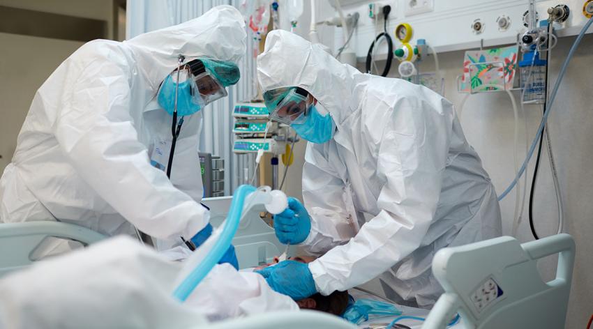 Two doctors in PPE work on a patient in the hospital