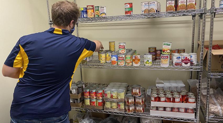 People stock the shelves of a campus food pantry at the University of Toledo in Ohio