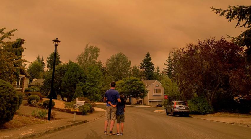 Portland residents step outside to view the wildfire smoke casting a colored haze over a neighborhood on Sept. 9, 2020.