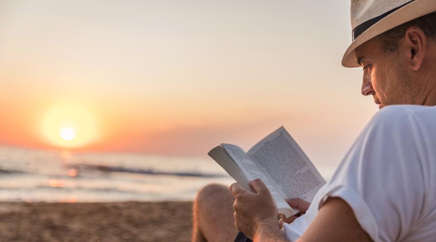 Man reading a book at the beach