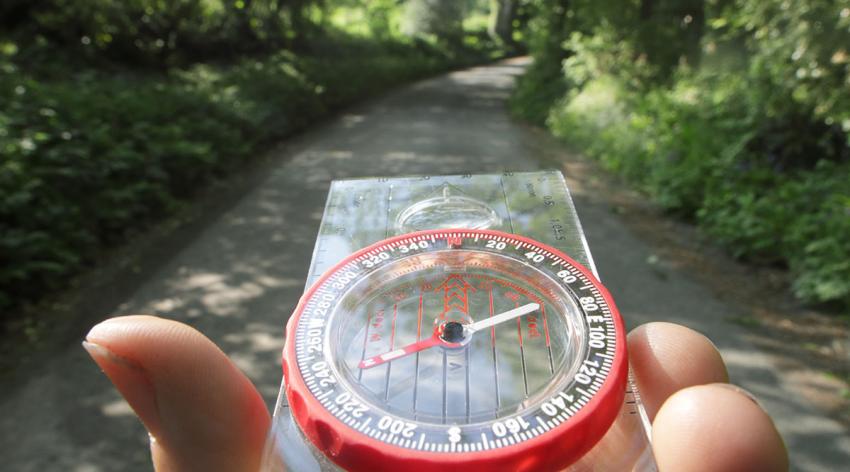 A person holds a compass on a path