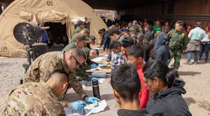 American soldiers filling up forms for migrants at a processing center.