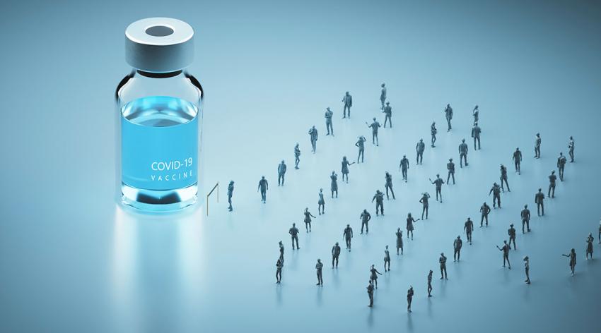 A group of people standing in a socially distant line leading to a COVID-19 vaccine bottle