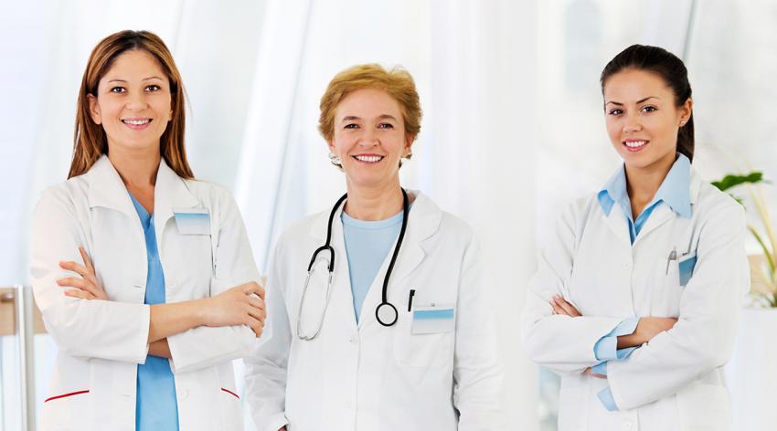 Three female doctors in white coats look straight at the camera