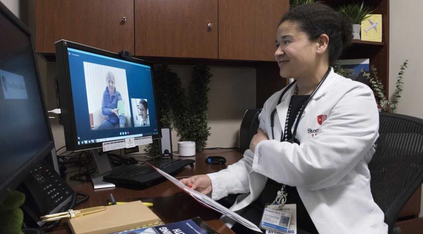Kimberly Noel, MD, MPH, talks to a patient through a computer in her office