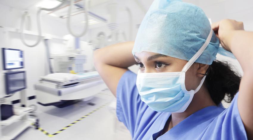 A woman doctor puts on a mask inside a hospital