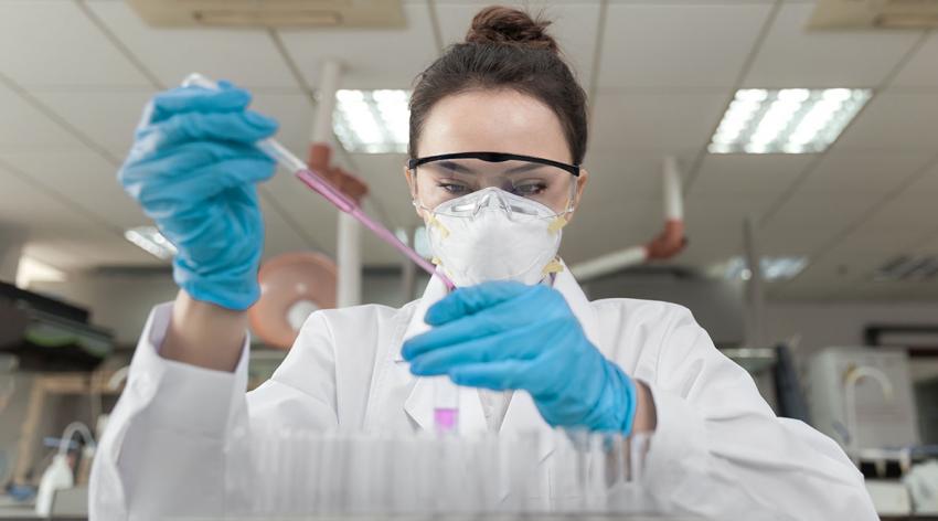 A woman runs tests using a test tube in a lab