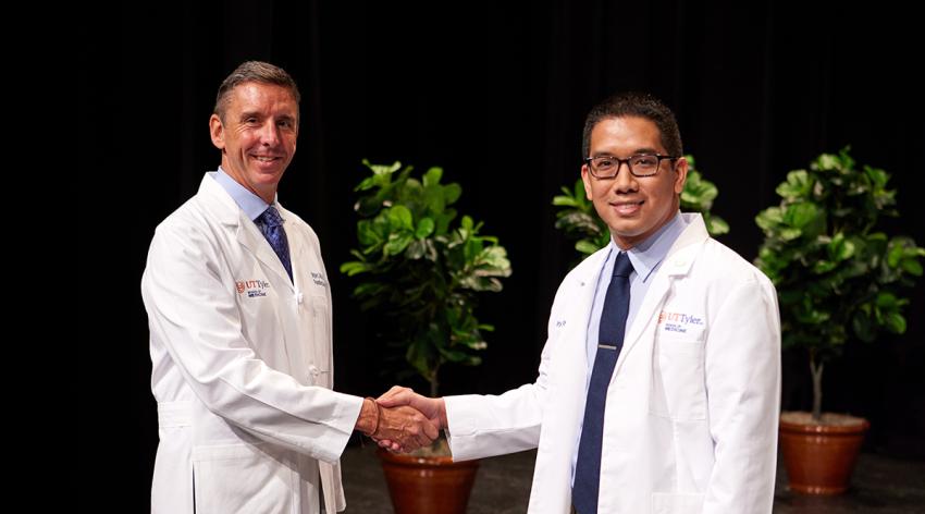 Tony Phan, right, shakes hands with Brigham C. Willis, MD, founding dean of the University of Texas at Tyler School of Medicine, at Phan’s White Coat Ceremony in July 2023.