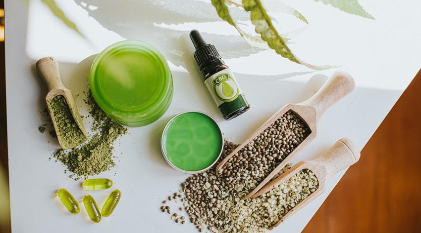 Various products containing CBD/cannabis/hemp: lotion, balm, soft-gel capsules, and crushed and whole hemp seeds