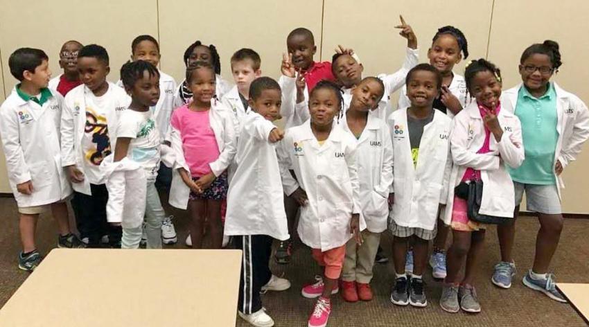 Elementary Students were doctors coats pose for the camera.