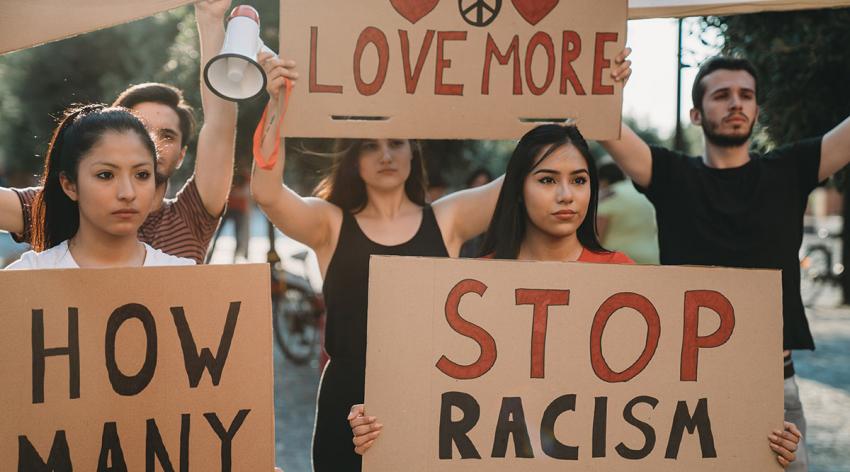 Protesters hold signs that say "Love More" and "Stop Racism"