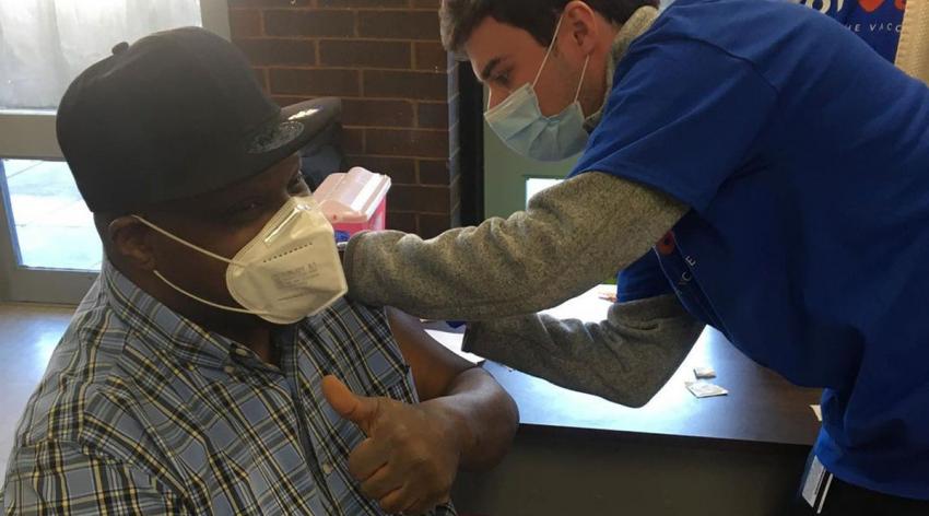 A volunteer for GOTVax, an organization focused on bringing vaccines to hard-hit communities, administers a vaccine to a resident of a Boston Housing Authority building in an under-resourced neighborhood.