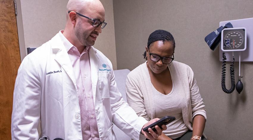 Austin Bush, MD, shows a patient at Atrium Health in North Carolina a tool on his phone.
